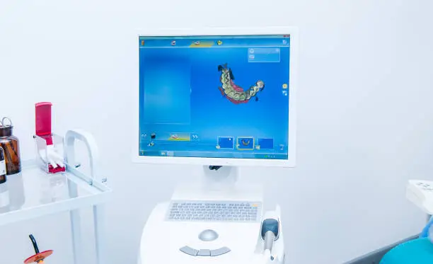 Photo of Prosthesis modeling process using CAD CAM dental computer-aided machine in a highly modern dental laboratory. Dentistry, prostodontics, prosthetics and medical computer technology concept.