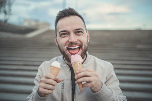 istock Handsome Young Boy Eating Ice Cream From Two Cones 877854482