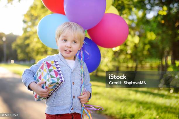 Cute Boy Holding Bundle Of Colorful Balloons And Gift In A Festive Box Happy Birthday Stock Photo - Download Image Now