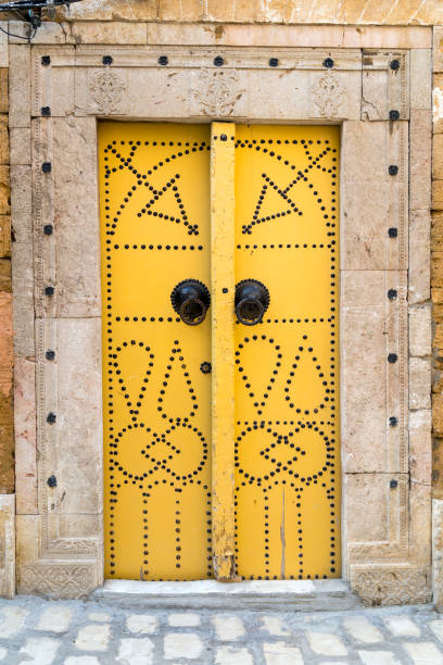 A tourist takes a break on the steps of a typical painted front door of a house in the labyrinthine alleys of Sidi Bou Said.\nPlease note that these images were taken in 1998 and converted from negatives.