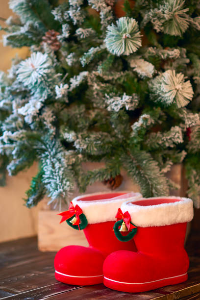 istock Red with white border Christmas boots under Christmas tree covered with snow 877899590
