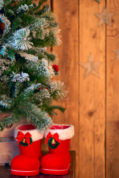 istock Red with white border Christmas boot under Christmas tree on wooden background with stars 877899672
