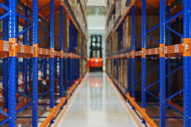 istock Electric forklift between large shelving in a modern storage building. 877930070