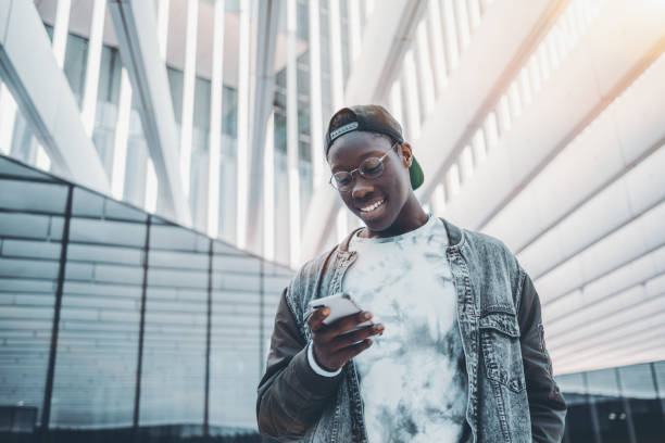 黒人の男が彼の携帯電話でメッセージを入力します。 - collegian ストックフォトと画像