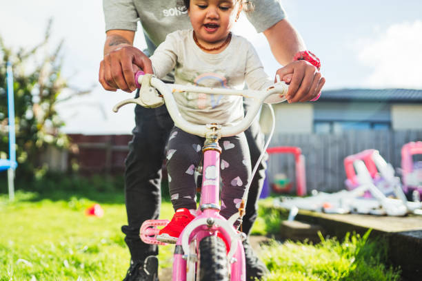 ojciec zabiera córkę na przejażdżkę. - candid people casual bicycle zdjęcia i obrazy z banku zdjęć