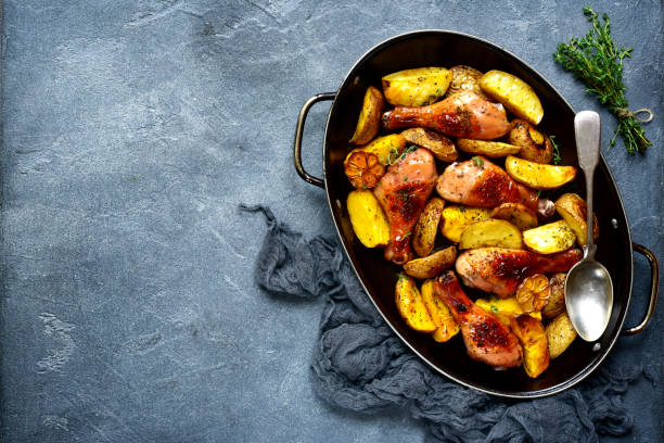 Chicken legs baked with potato in a skillet