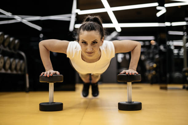 istock Young woman doing push-ups in the gym 877959132