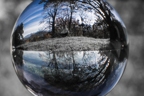 istock close up view on beautiful landscape trees in blue sky through lens ball sphere in selective color, france 877985324