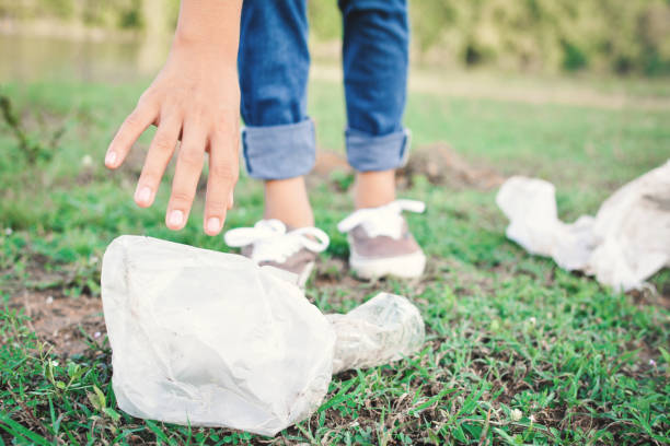 istock Low Section Of Woman Picking Garbage On Field At Park 877988148
