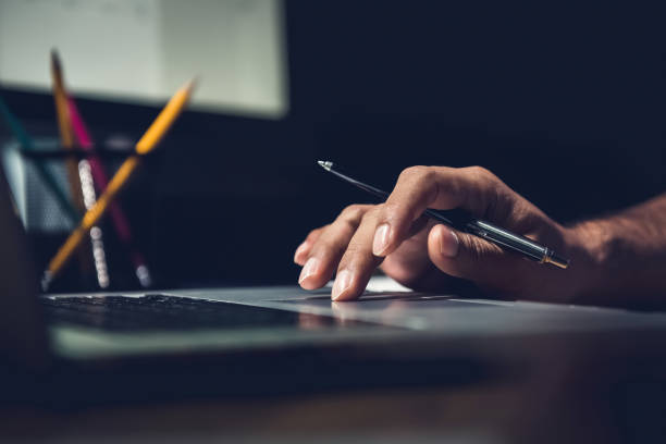 istock Hand of a man using laptop computer working overtime in the office late at night 877998160