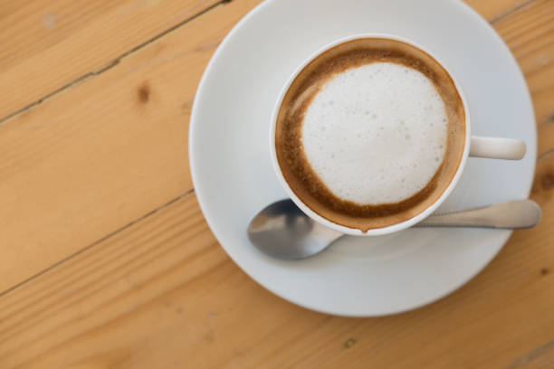 istock hot cappuccino coffee in white cup on wood table 877998214