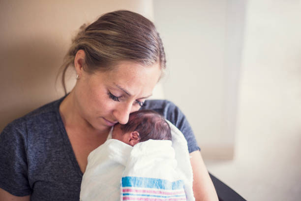 joven madre con su bebé recién nacido prematuro que está siendo tratado en el hospital. con amor y ternura tiene a su bebé cerca - premature fotografías e imágenes de stock