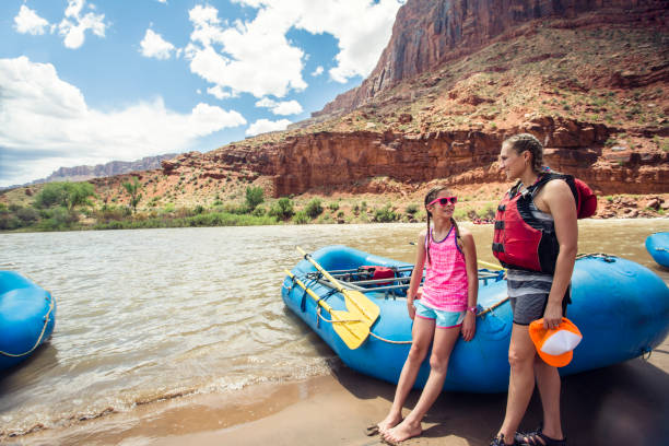 Family on a rafting trip down the Colorado River Smiling child and adult women ready to board a large inflatable raft as they travel down the scenic Colorado River near Moab, Utah and Arches National Park colorado river photos stock pictures, royalty-free photos & images