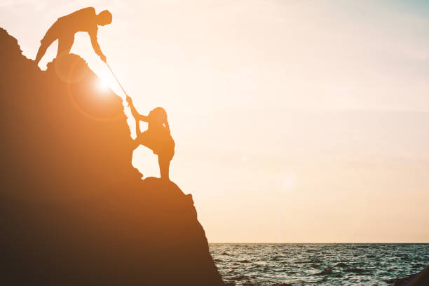 istock Silhouette Boy Pulling Girl On Rock Formation Against Sky 878011440