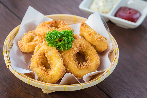 Fried calamari rings in wicker basket and sauce