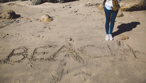 istock Low Section Of Woman Standing On Sand At Beach 878015170