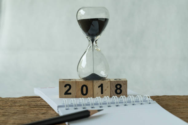 istock new year 2018 goals, target or checklist concept as number 2018 wooden cube block with sandglass and white paper note with pencil on wooden table 878015716