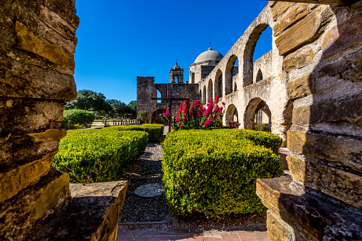 The Historic Old West Spanish Mission San Jose, Founded in 1720, San Antonio, Texas, USA.  Shot through the well showing dome, bell tower, and cross in the prayer garden.