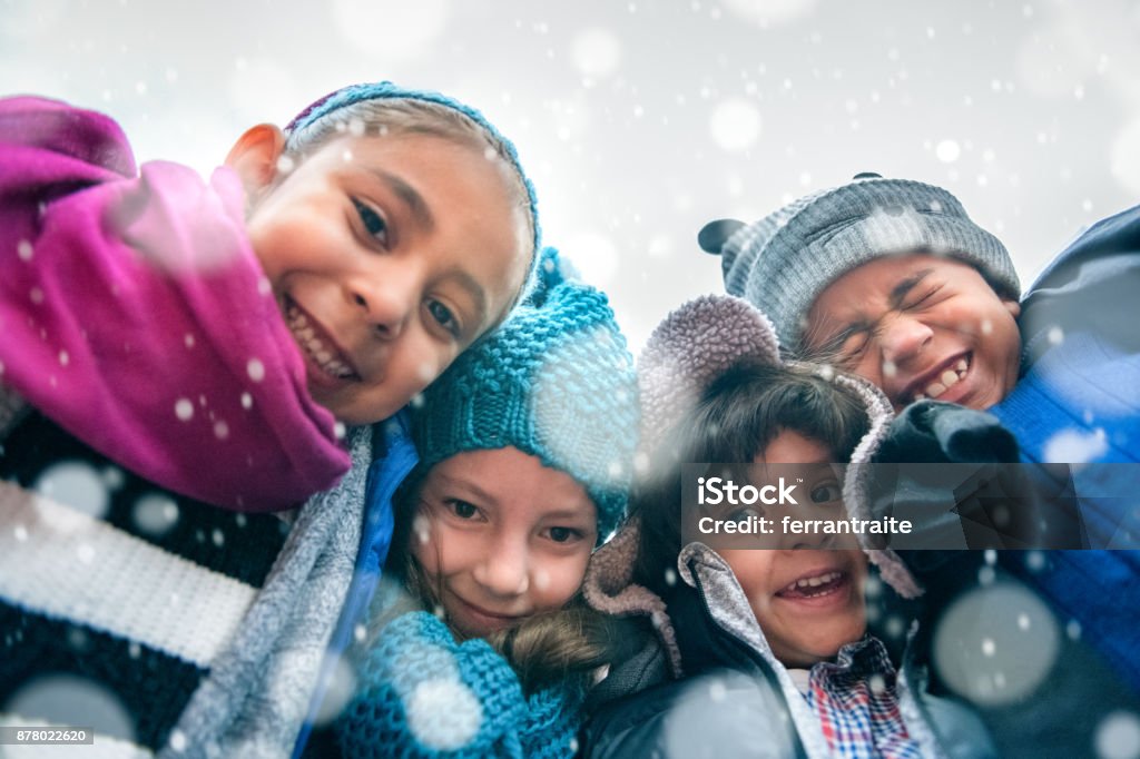 Children Group Hug Group of kids wrapped up in warm clothes hugging outdoors in winter, low point of view. Child Stock Photo