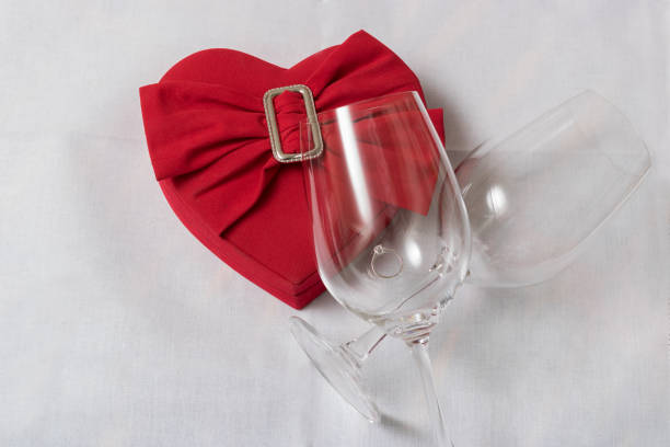 Wine glass and heart shaped box With wedding rings on the table