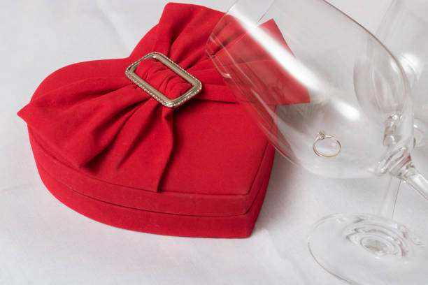 Wine glass and heart shaped box With wedding rings on the table