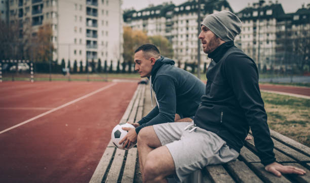 istock Football players sitting on a bench 878037672