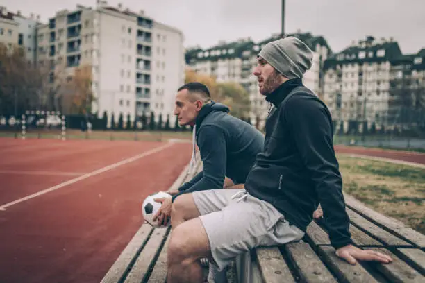 Two soccer players sitting on a bench with a soccer ball