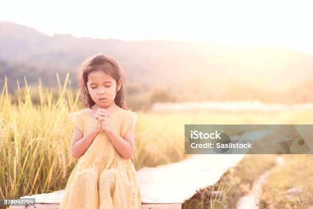 Cute Asian Little Child Girl Praying With Folded Her Hand And Sitting On Bamboo Walkway Stock Photo - Download Image Now