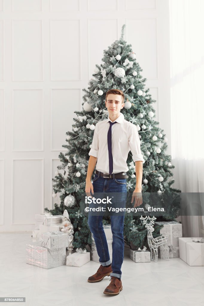 Guy teen meets Christmas. Guy teen meets Christmas. He is dressed in a white shirt, tie and jeans. Teenage Fashion Beautiful People Stock Photo
