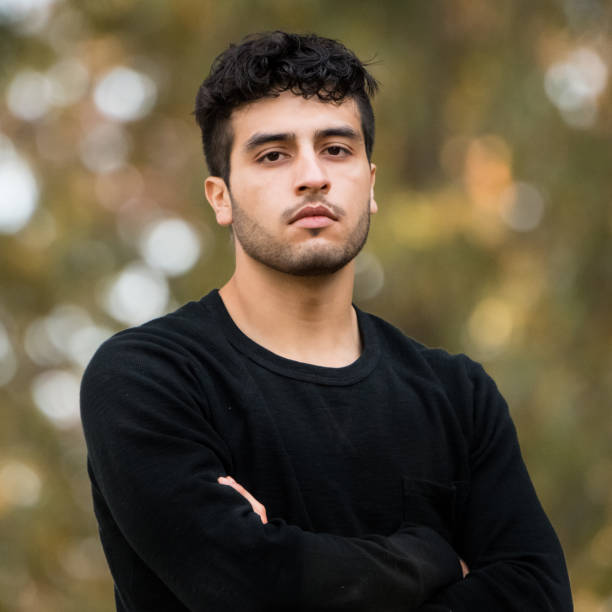 Young man looking at the camera Young man looking at the camera at the park with his arms crossed iranian ethnicity stock pictures, royalty-free photos & images