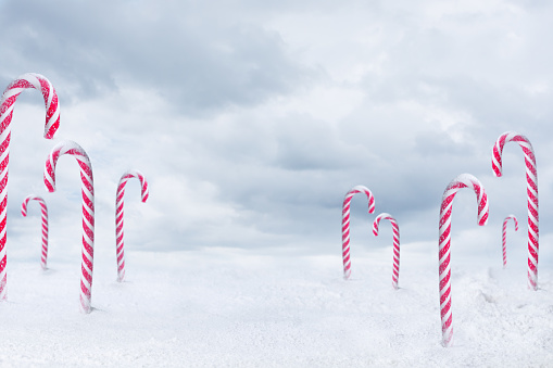 Christmas candy peppermint cane with snowfall on blue clouds background