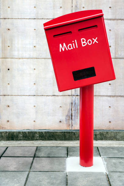 boîte aux lettres rouges sur le plancher de blocs de béton et le mur de ciment blanc - mailbox mail box side view photos et images de collection