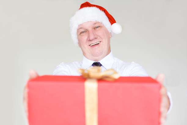 istock Joyful Business Man in Santa Hat Giving Gift 878119122