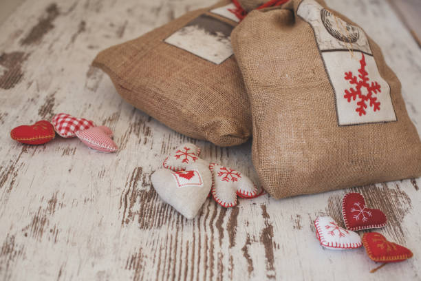 Close-up view of two linen bags and small heart shaped ornaments arranged on wooden table.