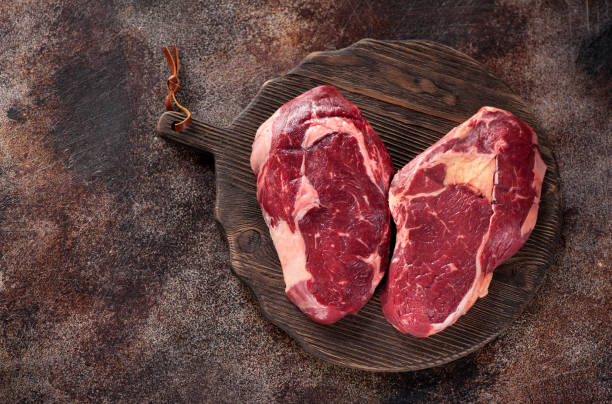 istock Raw fresh meat Ribeye Steak heart shape heart shape on brown rusty background 878143584