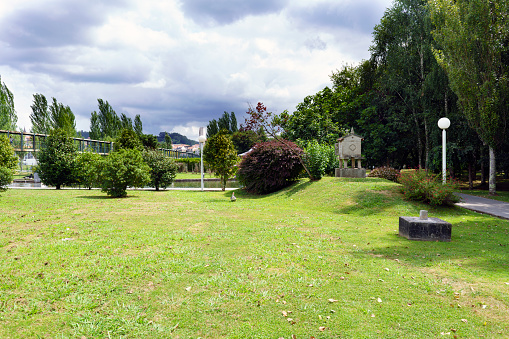 Garden with well-kept lawn and trees with cloudy sky. Park of the brothers Naveira in Betanzos, Galicia, Spain