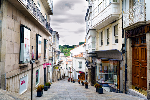 Betanzos, Galicia / Spain-August 25, 2017: Very steep street with stone floors with flower pots and small shops