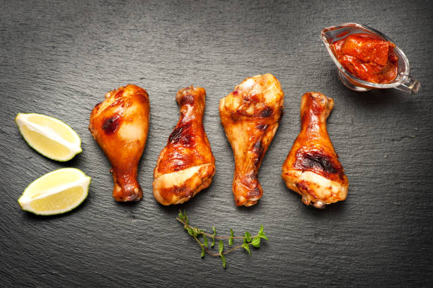 istock Grilled chicken drumstick legs on a black slate board 878147300