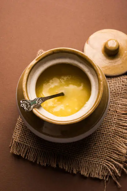 Photo of Desi Pure Ghee or clarified butter in glass or Copper container with spoon, selective focus