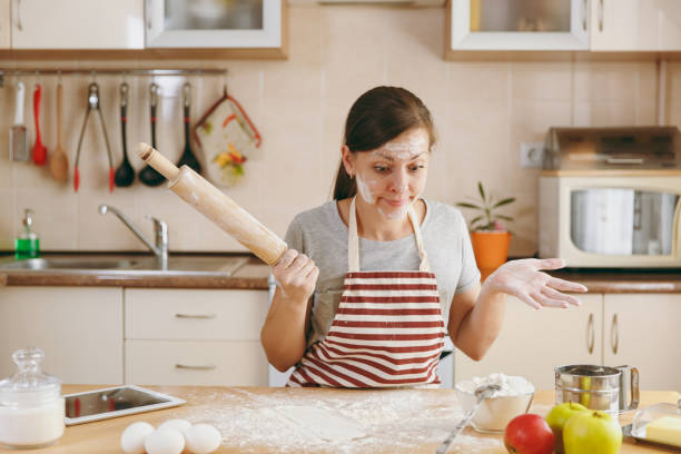 istock A young perplexed and confused woman sitting at a table with rolling pin and flour and going to prepare a Christmas cakes in the kitchen. Cooking home. Prepare food. 878164692