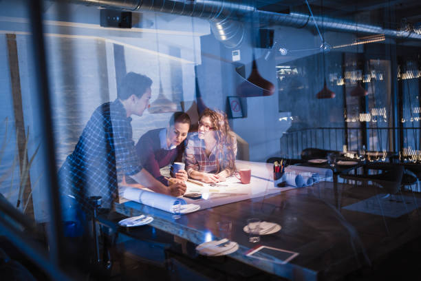 istock Working Late. Group of young architects working late in office 878175638