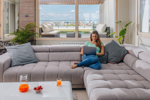 istock Beautiful woman relaxing on sofa and using laptop. 878176398
