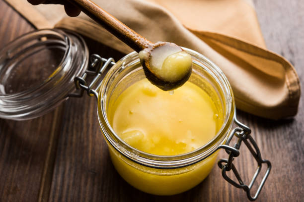 Desi Pure Ghee or clarified butter in glass or Copper container with spoon, selective focus stock photo