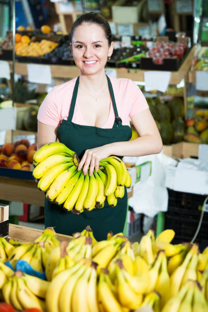 istock Female grocery worker offering bananas 878185128