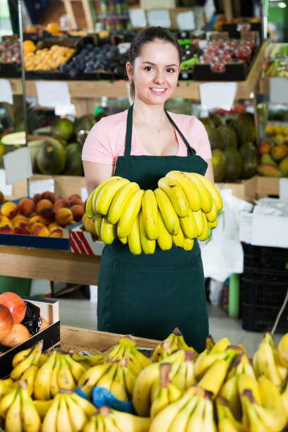 istock Female grocery worker offering bananas 878185156