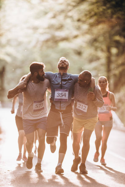 남성 주자 들고 자연에 마라톤 레이스 도중 선수를 부상. - marathon running jogging group of people 뉴스 사진 이미지