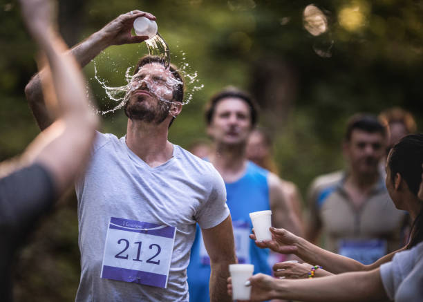 Exhausted athletic man running a marathon and refreshing himself with water.