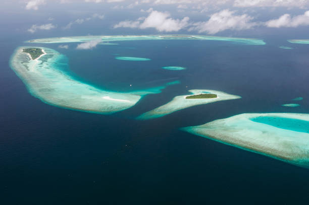Tropical islands and atolls in Maldives in Indian Ocean from aerial view. Piece of paradise on the Earth. Good choice for vacation. Beautiful top view for wallpaper. The tropical islands and atolls in Maldives in Indian Ocean from aerial view. Piece of paradise on the Earth. Good choice for vacation. Beautiful top view for wallpaper. atoll stock pictures, royalty-free photos & images
