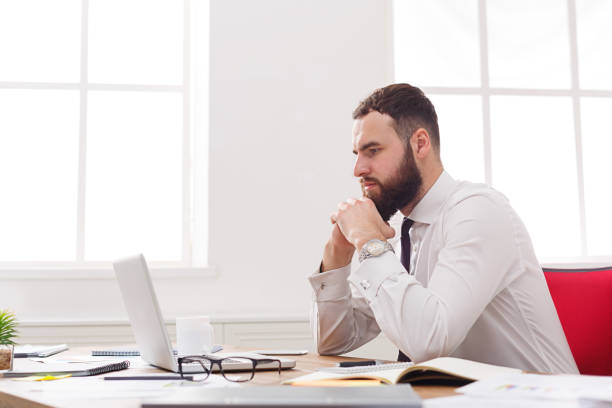 istock Pensive businessman with laptop in modern white office 878198994