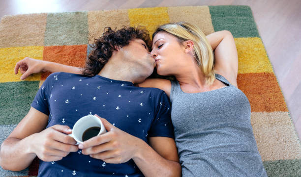 couple kissing lying on the carpet - couple loving lying on back carpet imagens e fotografias de stock